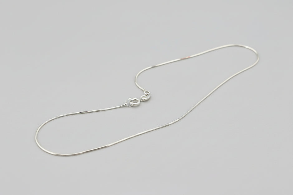 Silver necklace on a textured gray surface